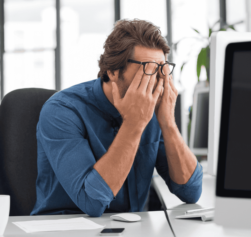 Tired man holding head at his office desk